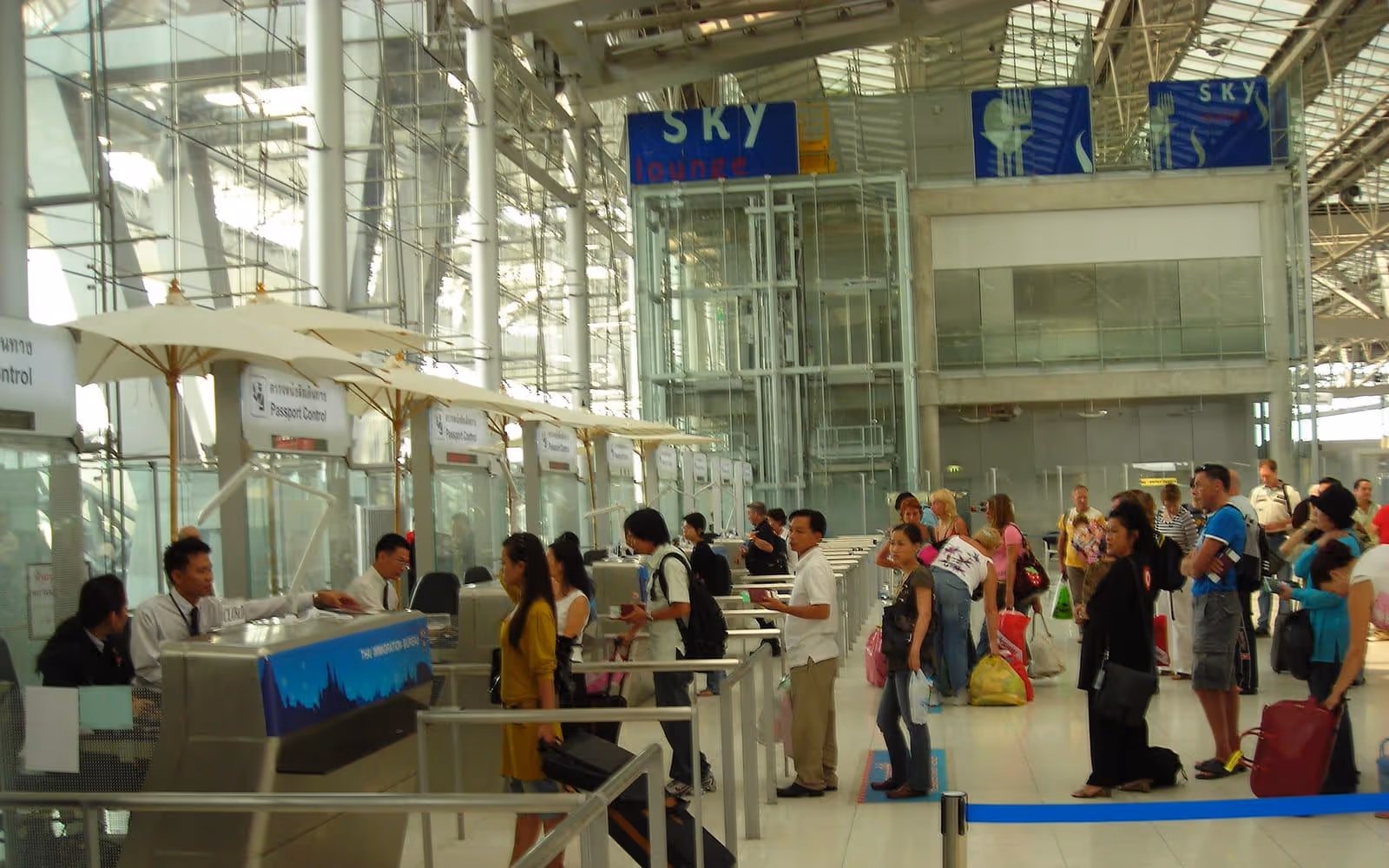 Travellers queueing at passport-control desks in an international airport arrivals hall