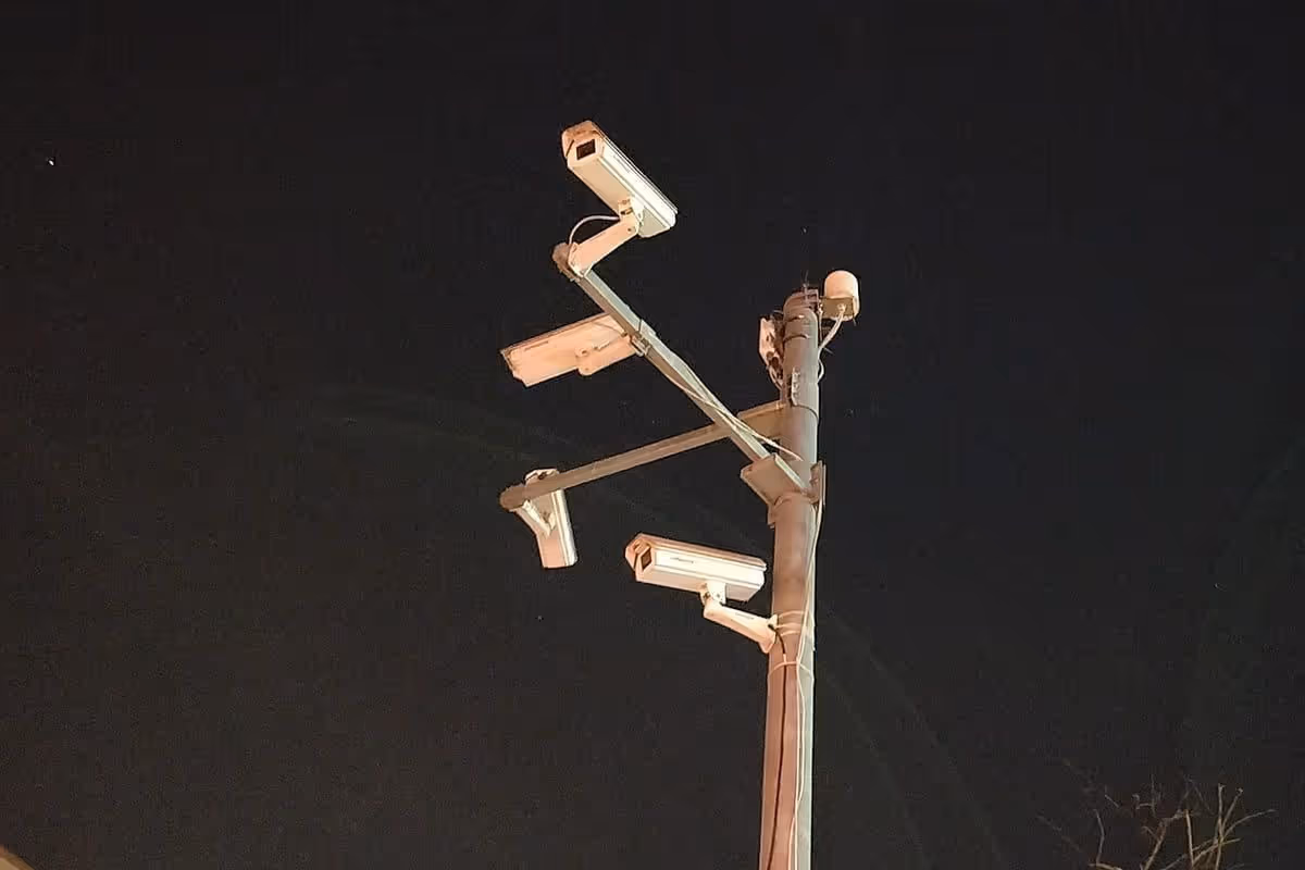 Fixed surveillance cameras mounted on a pole against an open sky