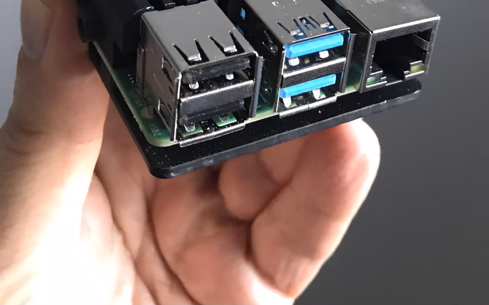 A single-board computer held in one hand, showing its USB and Ethernet connectors